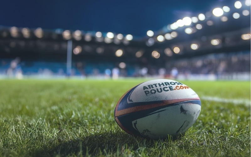 Rugbyball auf dem Spielfeld bei Nacht.