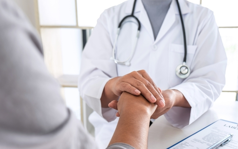 Arzt berührt freundlich die Hand eines Patienten.