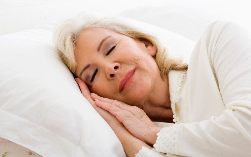 Ältere Frau schläft entspannt im Bett.