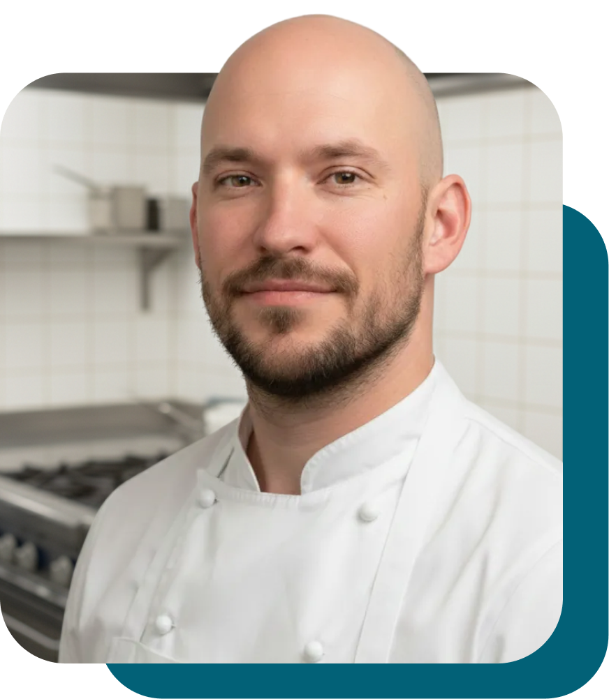 Koch im Küchenumfeld mit freundlichem Lächeln.